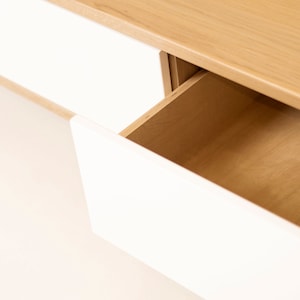 May include: A white drawer with a wooden interior is partially open, revealing the wood grain. The drawer is part of a white and wood cabinet.