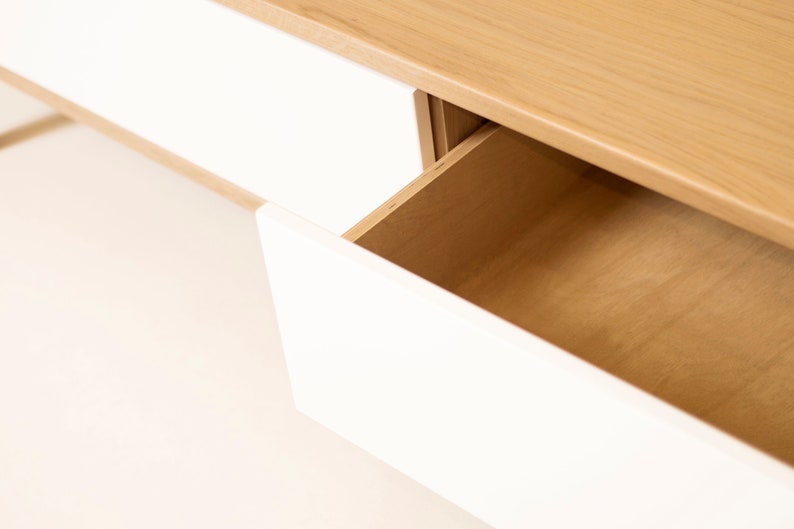 May include: A white drawer with a wooden interior is partially open, revealing the wood grain. The drawer is part of a white and wood cabinet.