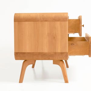 May include: A light wood dresser with two drawers that are open. The dresser has a curved top and sits on four legs.