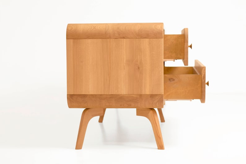 May include: A light wood dresser with two drawers that are open. The dresser has a curved top and sits on four legs.