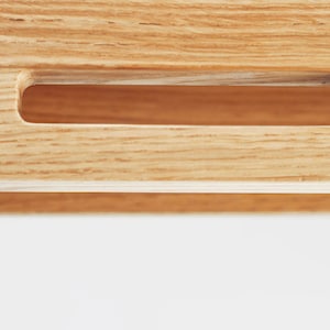 Puede incluir: Primer plano de un objeto de madera con un asa rectangular empotrada. La veta de la madera es visible y el asa es de un tono marr&oacute;n m&aacute;s claro que la madera circundante. El fondo es blanco.