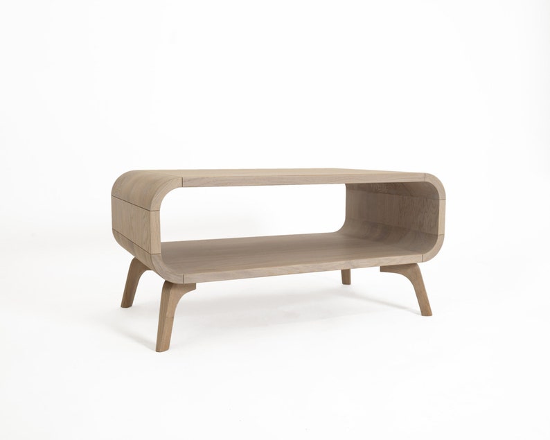 May include: A light wood coffee table with a curved, open shelf and four legs. The table has a modern design.