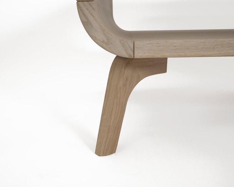 May include: A wooden bench with a curved back and four legs. The bench is made of light-colored wood and has a natural finish.