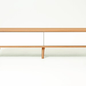 May include: A white and natural wood media console with two drawers and rounded edges. The console has four legs and a modern design.