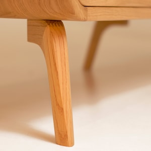 Puede incluir: Primer plano de las patas de madera de un armario. Las patas son de color marr&oacute;n claro y tienen un dise&ntilde;o curvo.
