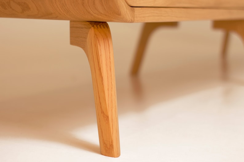 Puede incluir: Primer plano de las patas de madera de un armario. Las patas son de color marr&oacute;n claro y tienen un dise&ntilde;o curvo.