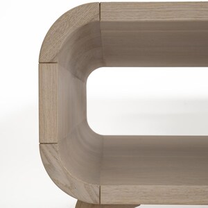 May include: A light wood coffee table with a curved, oval-shaped design. The table has a shelf underneath the top surface.