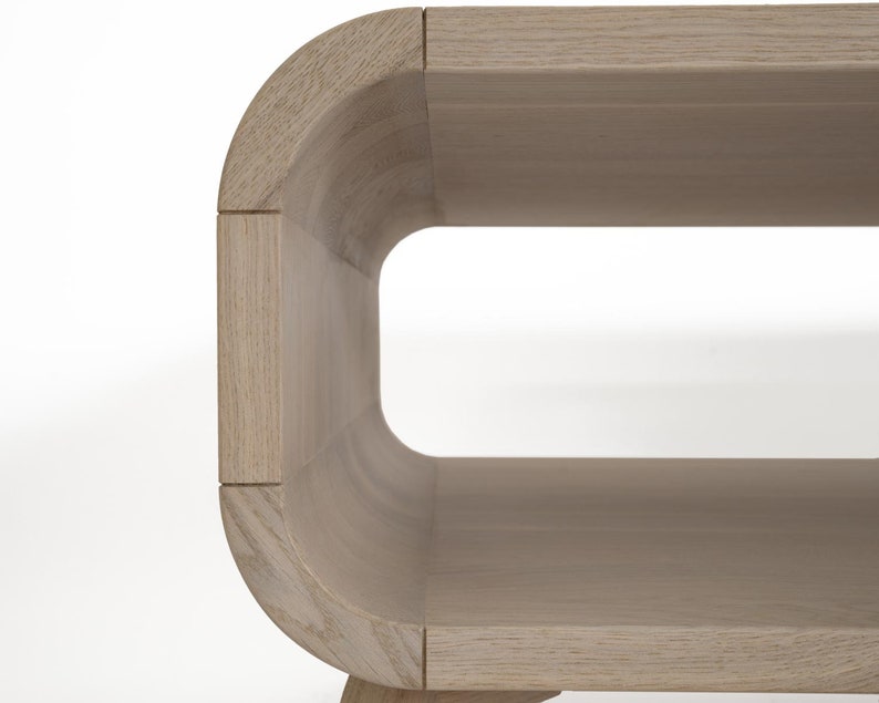 May include: A light wood coffee table with a curved, oval-shaped design. The table has a shelf underneath the top surface.