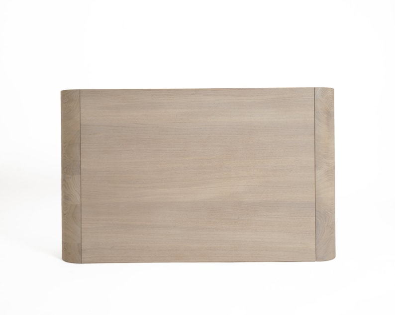 May include: A light brown wooden headboard with a curved top and a smooth, slightly textured surface.