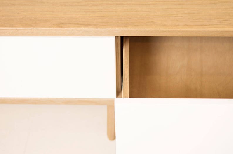 May include: A wooden cabinet with two drawers and a shelf. The drawers are white and the shelf is wood. The cabinet is on a white background.