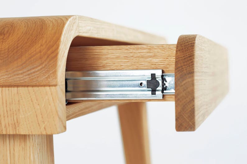 Puede incluir: Primer plano de un escritorio de madera con un caj&oacute;n parcialmente abierto. El escritorio es de madera clara, con vetas visibles. Los rieles del caj&oacute;n son met&aacute;licos. El escritorio tiene un dise&ntilde;o moderno y minimalista.