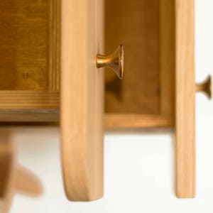 May include: Close-up of a wooden cabinet with two drawers. The drawers are open, revealing the interior. The cabinet has brass drawer pulls.
