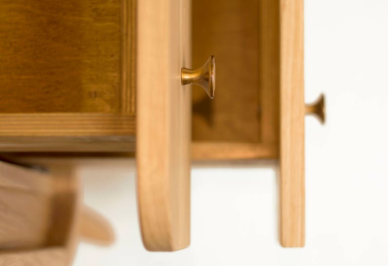 May include: Close-up of a wooden cabinet with two drawers. The drawers are open, revealing the interior. The cabinet has brass drawer pulls.