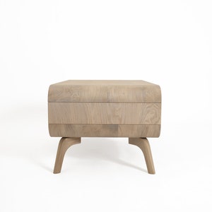 May include: A light wood coffee table with a curved top and four legs. The table has a natural wood finish.
