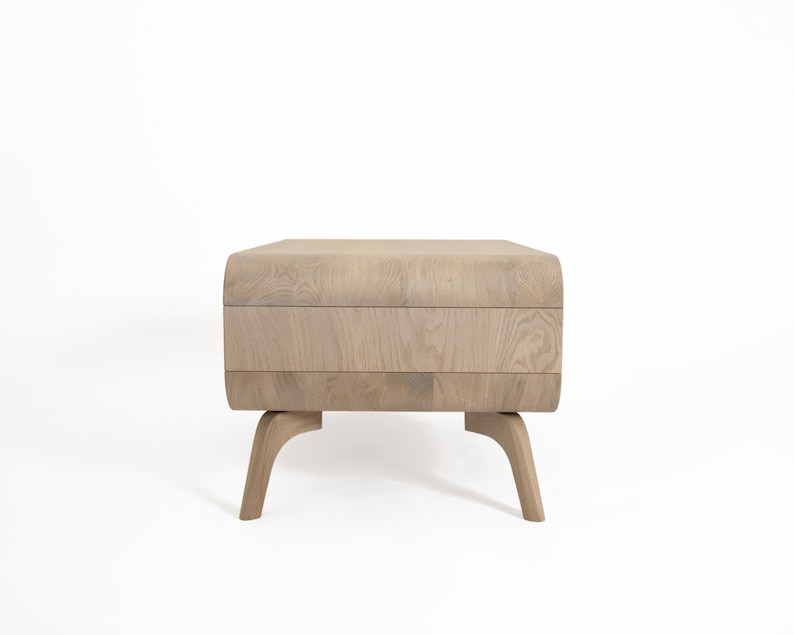 May include: A light wood coffee table with a curved top and four legs. The table has a natural wood finish.