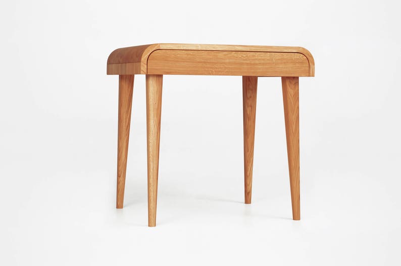 Puede incluir: Una mesa auxiliar de madera marr&oacute;n claro con una parte superior curvada y cuatro patas c&oacute;nicas. La mesa tiene un solo caj&oacute;n y est&aacute; hecha de madera maciza. El dise&ntilde;o es minimalista y moderno, adecuado para un sal&oacute;n o dormitorio.