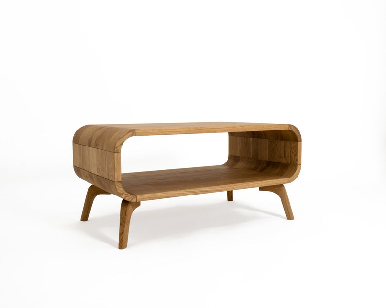 May include: A light wood coffee table with a curved, open shelf and four legs. The table has a modern design.
