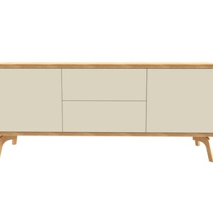 Puede incluir: Una consola de medios de madera clara con tres cajones y bordes redondeados. Los cajones son de color beige claro y la consola tiene cuatro patas.
