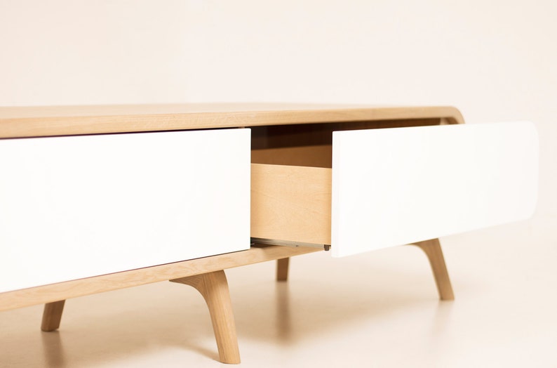 May include: A white and natural wood coffee table with two drawers. One drawer is open, revealing the natural wood interior.