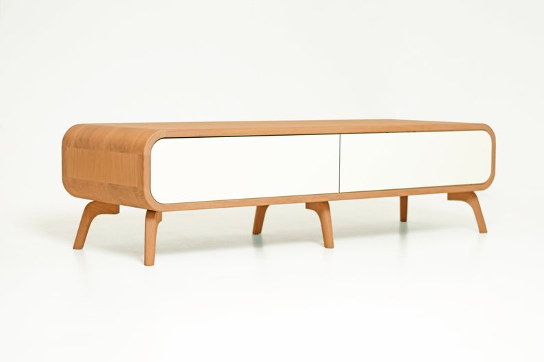 May include: A light wood coffee table with two white drawers and curved edges. The table has four legs that are slightly angled.