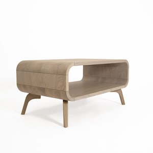 May include: A light wood coffee table with a curved, open shelf and four legs. The table has a modern design.
