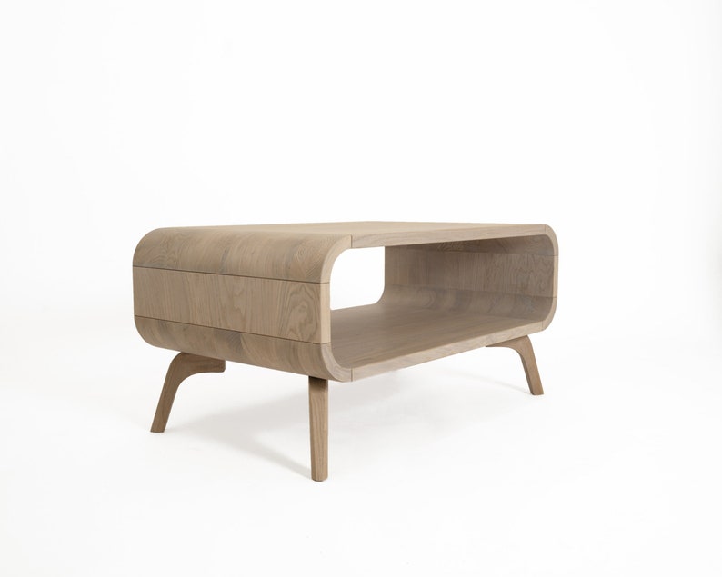 May include: A light wood coffee table with a curved, open shelf and four legs. The table has a modern design.