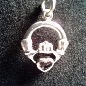 May include: Silver Celtic knot pendant necklace with a heart in the center. The pendant is on a black cord.
