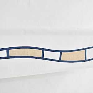 Peut inclure: Panneau de rideau blanc et transparent avec un motif géométrique ondulé bleu et beige. Le rideau est suspendu à une tringle blanche.