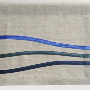 Peut inclure: Une cantonnière en lin naturel avec trois accents de ruban bleu ondulés. La cantonnière est de couleur beige clair et les rubans sont bleu foncé, bleu moyen et bleu clair.