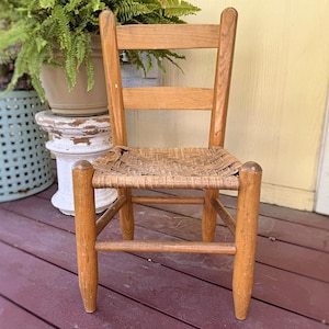 May include: A wooden chair with a woven rush seat. The chair is made of natural wood and has a simple, rustic design.