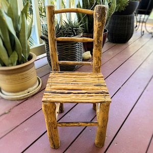 May include: A rustic wooden chair with a woven seat made of natural branches. The chair is made of rough-hewn wood and has a simple, natural design.