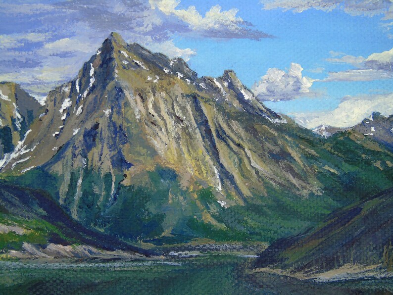 May include: An oil painting depicts a mountain landscape with a large, snow-capped peak dominating the scene. The mountain is painted in shades of gray, brown, and green, with a blue sky and fluffy white clouds in the background. A lake is in the foreground.