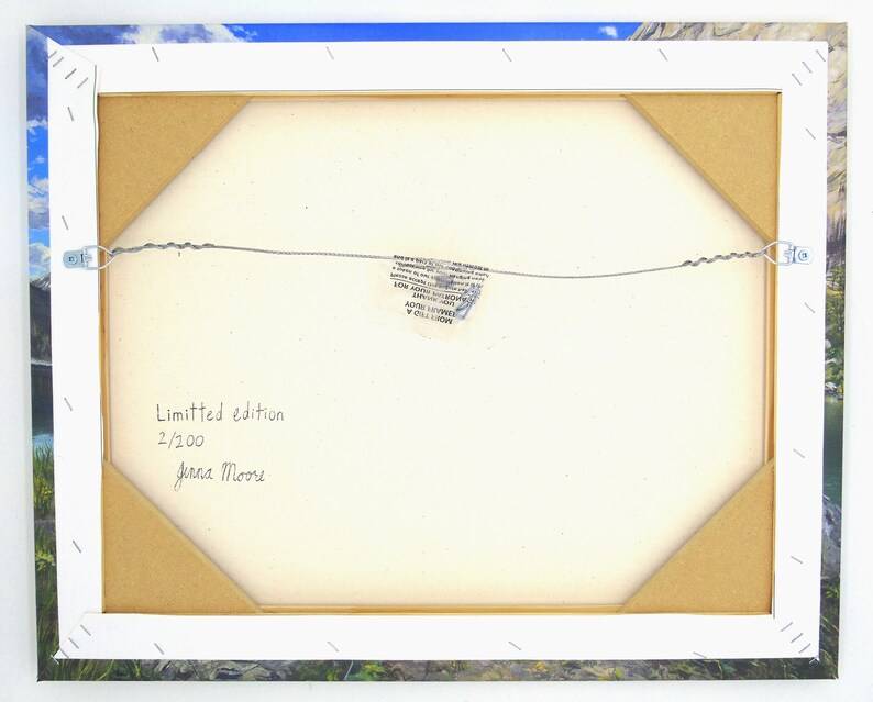 May include: Back of a framed canvas print with a landscape image. The canvas is stretched over a wooden frame, secured with staples. The text "Limited edition 2/200 Jenna Moore" is handwritten on the canvas.
