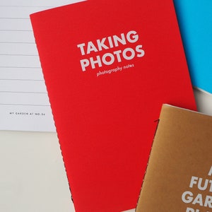 May include: Red notebook with the text "TAKING PHOTOS photography notes" on the cover.