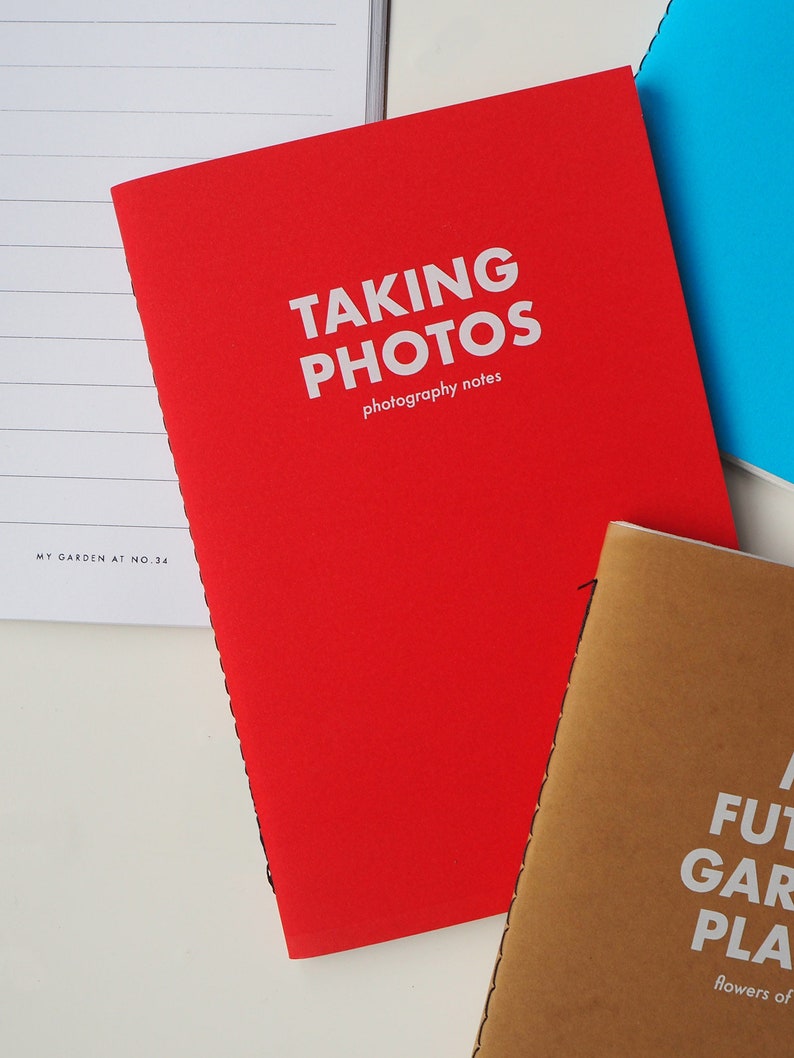May include: Red notebook with the text "TAKING PHOTOS photography notes" on the cover.