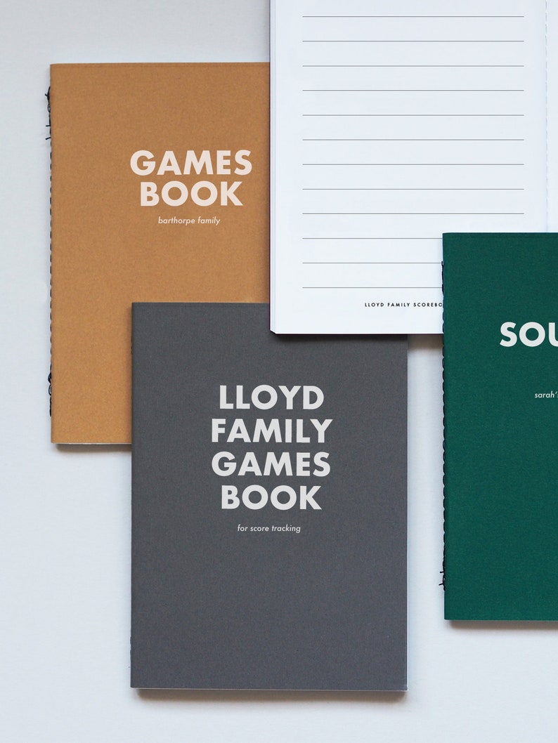 May include: Three different notebooks with the words "GAMES BOOK" on the front. The notebooks are brown, gray, and green. The brown notebook says "barthorpe family" on the front. The gray notebook says "LLOYD FAMILY GAMES BOOK for score tracking" on the front. The green notebook says "SOL sarah'" on the front.