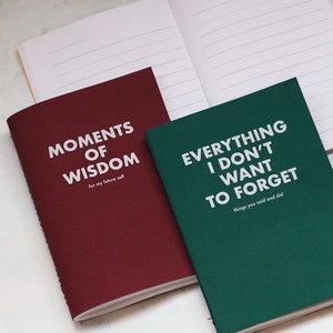 May include: Two small, lined notebooks with burgundy and green covers. The burgundy notebook has the text "Moments of Wisdom (for my future self)" printed on the front. The green notebook has the text "Everything I don't want to forget (things you said and did)" printed on the front.