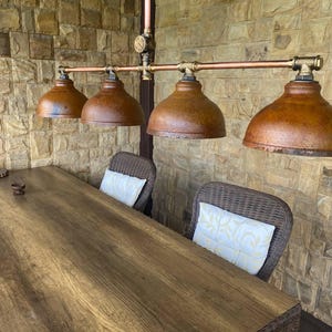 Industrial ceiling chandelier with rusty lampshade and copper pipe.