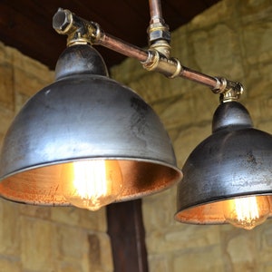 May include: Two industrial-style pendant lights with copper pipes and black metal shades. The shades have a copper interior and are illuminated by Edison-style light bulbs.