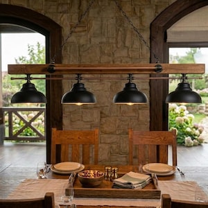 May include: A linear pendant light fixture featuring a horizontal wooden beam suspended by chains, with four matte black dome-shaped metal shades attached to a copper-toned metal rod, providing downward illumination over a dining table.