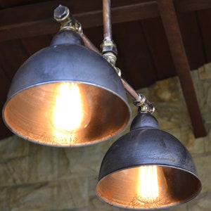 May include: Two black metal pendant lights with copper pipes and exposed bulbs hanging from a wooden ceiling.