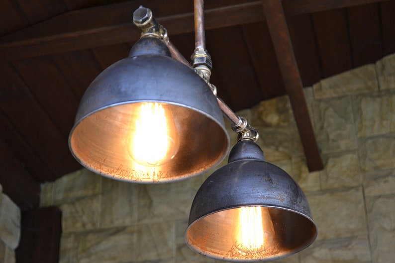 May include: Two black metal pendant lights with copper pipes and exposed bulbs hanging from a wooden ceiling.
