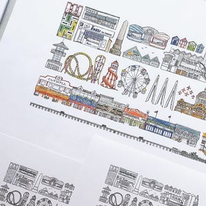 May include: A colorful illustration of a seaside amusement park with a Ferris wheel, roller coaster, and various buildings. The illustration is drawn in a cartoon style with black outlines and colored in with bright colors.