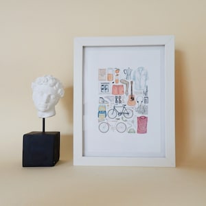 Pode incluir: Uma impress&atilde;o emoldurada branca com uma ilustra&ccedil;&atilde;o em aquarela de uma bicicleta, um viol&atilde;o, uma cafeteira, um copo de suco de laranja, &oacute;culos de sol, uma mochila e outros itens. A impress&atilde;o est&aacute; pendurada em uma parede bege claro ao lado de um busto de gesso branco de um homem.