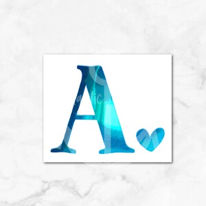 May include: A blue holographic letter A with a small heart next to it. The letter and heart are on a white background. Peacock blue holographic.