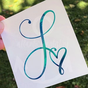 May include: A peacock blue holographic vinyl decal of the letter "J" with a heart in the center.