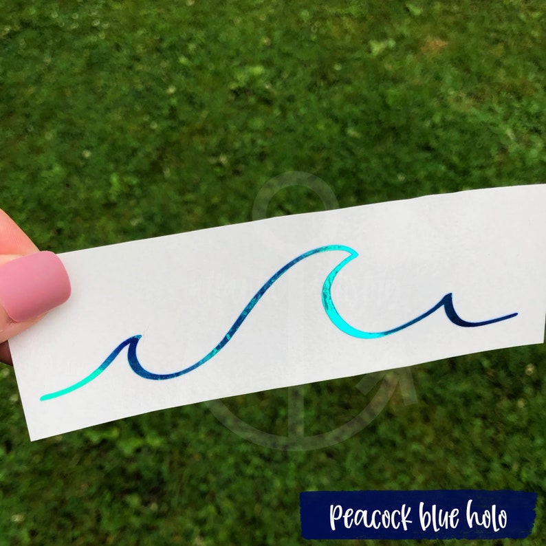 May include: A wave decal with a peacock blue holographic finish. The wave is a simple, stylized design with a single crest.