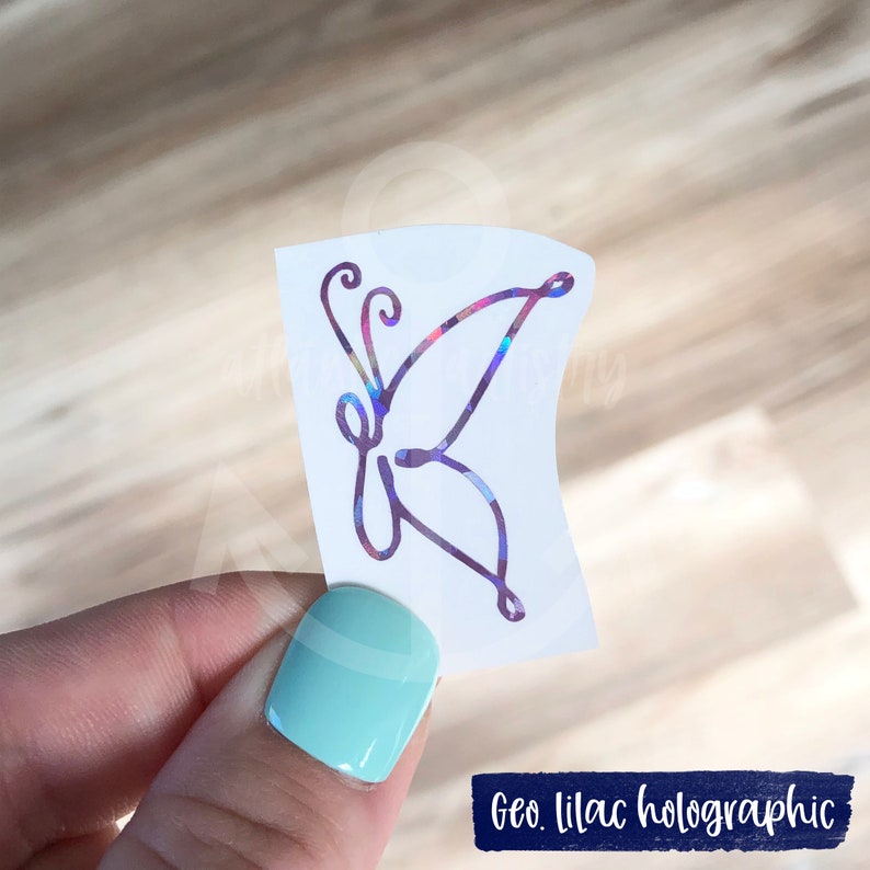 Puede incluir: Una pegatina de mariposa hologr&aacute;fica con un dise&ntilde;o geom&eacute;trico lila. La pegatina est&aacute; sobre un fondo blanco.