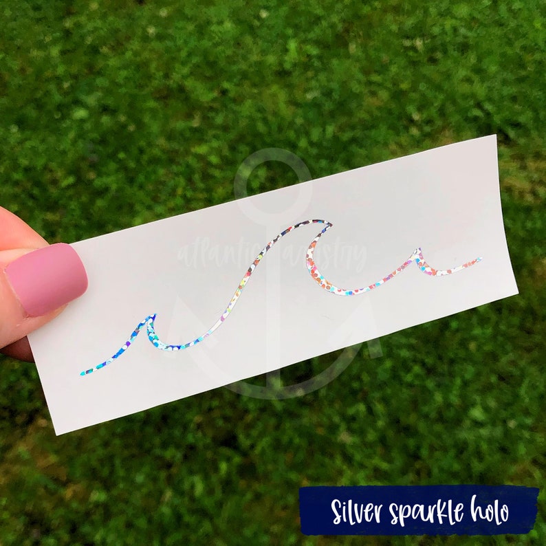 May include: A silver sparkle holographic wave design on a white background. The wave is made of glitter and has a rainbow effect.