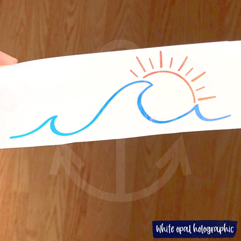 May include: A white opal holographic sticker featuring a blue wave design with a setting sun in shades of orange. The sticker has the text "White opal holographic" in a navy blue rectangle.